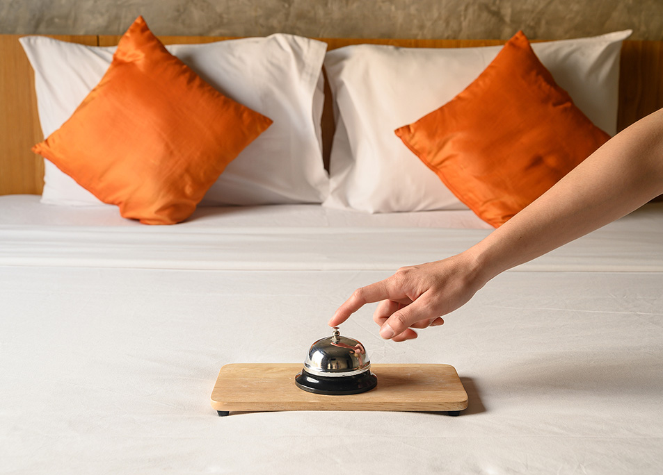 Close-up Of Guest Hand Trying To Ringing Hotel Bell In Hotel Bed